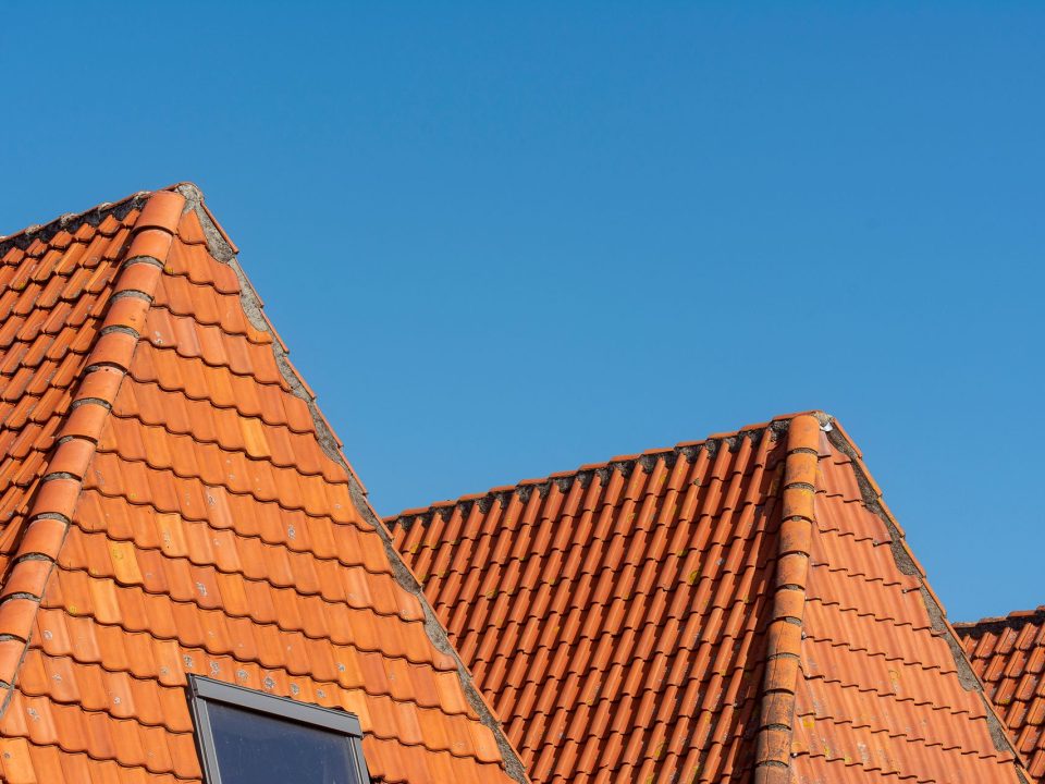 Zwei rote Ziegeldächer mit Dachfenster vor blauem Himmel