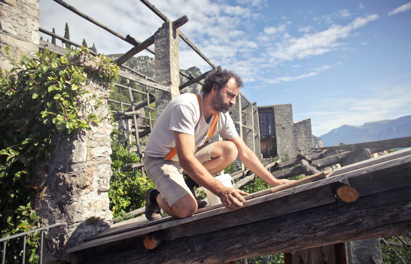 Dachdecker arbeitet auf den offenen Holzbalken eines Dachstuhls