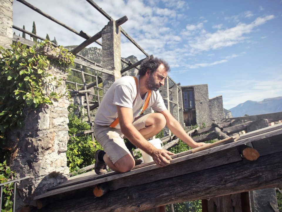 Dachdecker arbeitet auf den offenen Holzbalken eines Dachstuhls