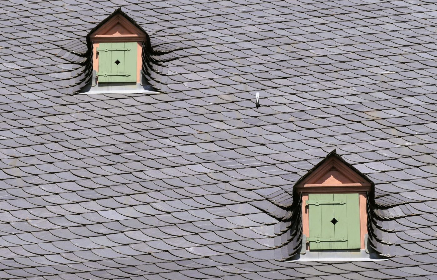 Schieferdach mit zwei Dachgauben und grünen Fensterläden