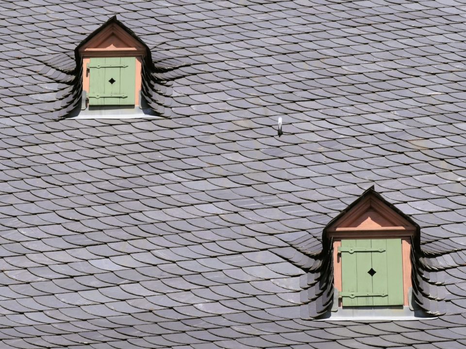 Schieferdach mit zwei Dachgauben und grünen Fensterläden